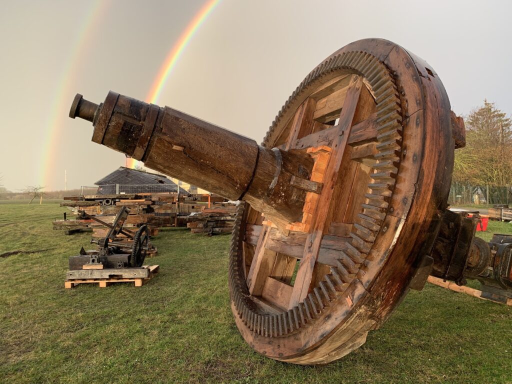 Historisches Bremsrad der Ehlertschen Mühle im Freien, im Hintergrund ein Regenbogen