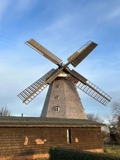 Windmühle mit ausgestellten Flügeln vor blauem Himmel